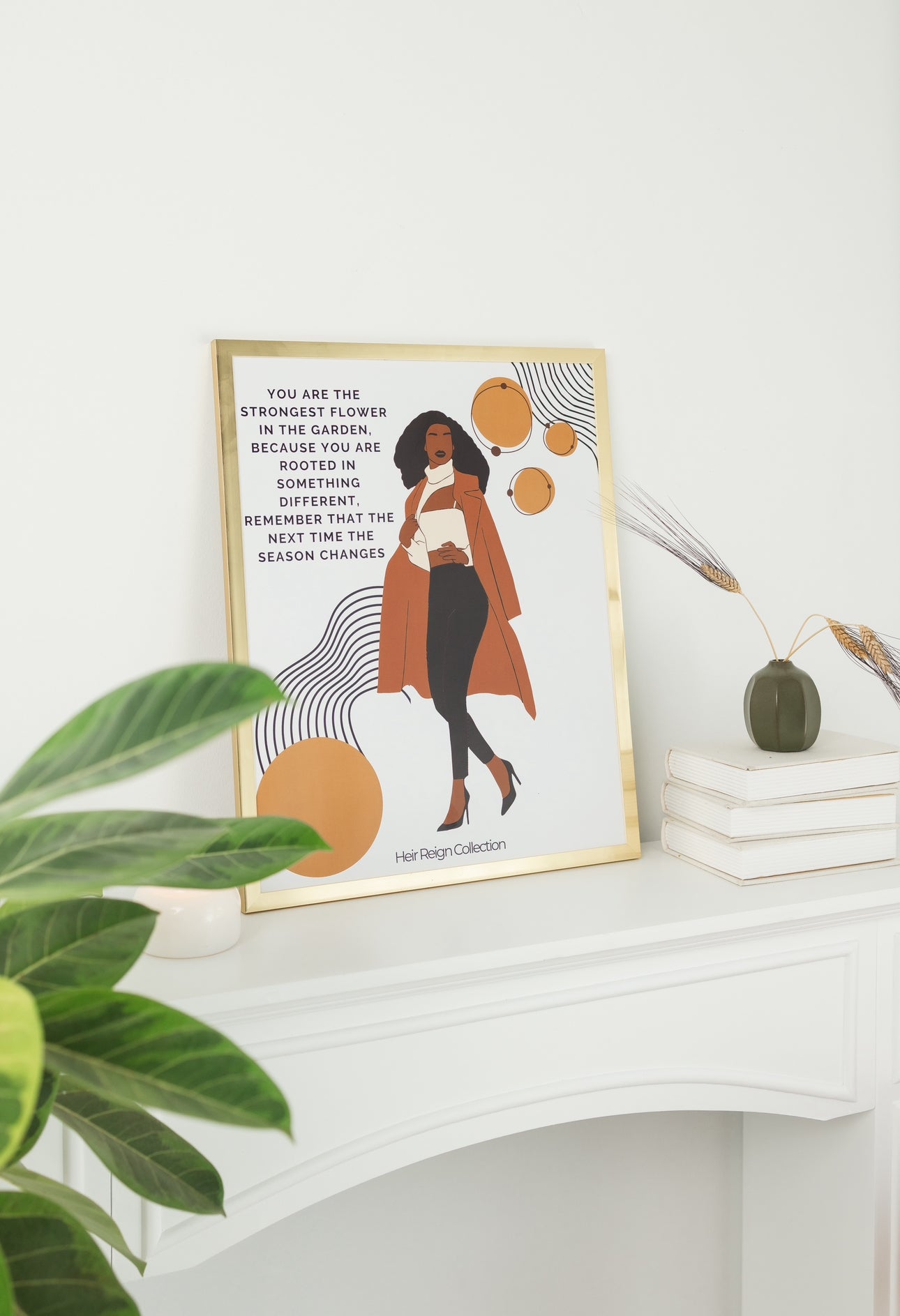 Beautiful wall art illustration of a black business professional woman. She is wearing a brown trench coat, black pants and high heel shoes. The picture also has an inspirational positive affirmation next to the woman. The picture is in a gold frame with beautiful home decor.